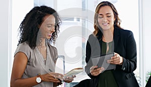 Nothing completes a work task like teamwork. two young businesswomen using a digital tablet in a modern office.