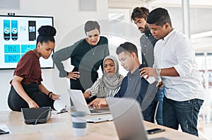 Nothing expands business like teamwork. a group of businesspeople using a laptop during a meeting in a modern office.
