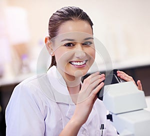 Nothing hides from me with this baby. Portrait of a young scientist using a microscope in a laboratory.