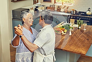 Nothing inspires romance like food. Shot of a happy mature couple dancing together while cooking in the kitchen at home.