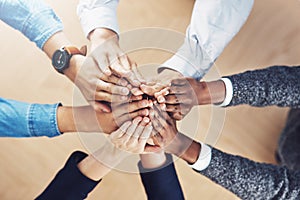 Nothing inspires success like teamwork. High angle shot of a group of unidentifiable businesspeople joining their hands