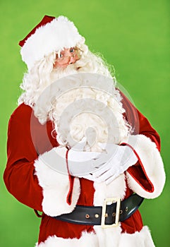 Nothing like homemade Christmas pudding. Portrait of Father Christmas holding his belly - isolated on a green backgorund