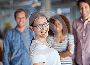 Nothing like a positive work environment to bring out ones best. Happy young woman smiling at the camera with coworkers