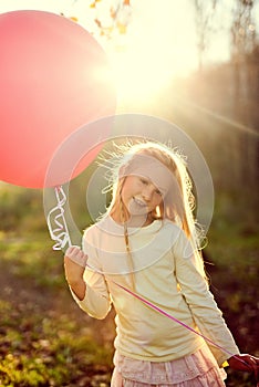 Nothing but sunshine and fun times. Portrait of a young girl playing with a balloon outside.