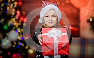 Nothing warms the heart like giving xmas gift. Happy little girl giving xmas present. Small child holding present on
