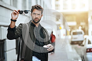 Nothing will impair his vision. a handsome young man checking his sunglasses while traveling through the city. photo