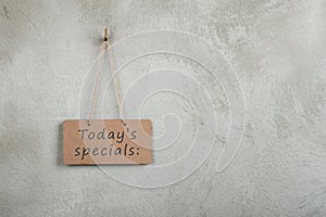 notice board, blackboard, chalkboard with text Today's specials on copy space grey cement wall