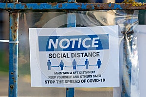 a notice on a fence stating the rules around social distancing during the coronavirus or Covid-19 outbreak as per government