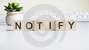 Notify word made with wooden blocks on background white keyboard