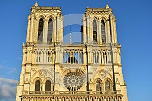 Notre Dame Cathedral, Paris, France. Gothic facade closeup with sunset light. Towers, statues, rose window, archs and doors.