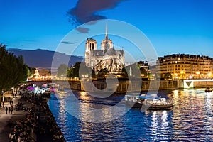 Notre Dame de Paris with cruise ship on Seine river at night in