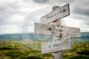 Nourish your soul text engraved on old wooden signpost outdoors in nature photo