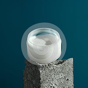 Nourishing face or body cream on a granite cube, blue background