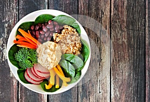 Nourishment bowl with quinoa, hummus, mixed vegetables, over rustic wood