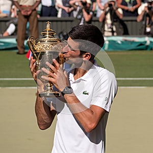 Novac Djokovic, Serbian player, wins Wimbledon for the fourth time. In the photo he kisses his trophy on centre court.