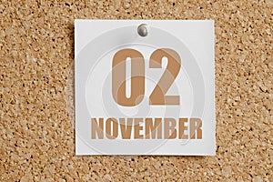 november 02. 02th day of the month, calendar date.White calendar sheet attached to brown cork board.Autumn month, day of