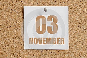 november 03. 03th day of the month, calendar date.White calendar sheet attached to brown cork board.Autumn month, day of