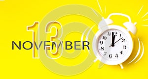 November 13rd. Day 13 of month, Calendar date. White alarm clock with calendar day on yellow background. Minimalistic concept of