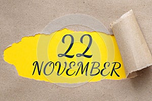 november 22. 22th day of the month, calendar date.Hole in paper with edges torn off. Yellow background is visible