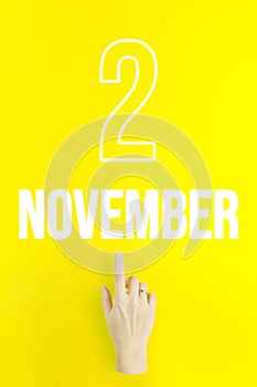 November 2nd. Day 2 of month, Calendar date.Hand finger pointing at a calendar date on yellow background.Autumn month, day of the