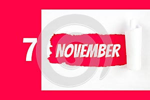 November 7th. Day 7 of month, Calendar date. Red Hole in the white paper with torn sides with calendar date. Autumn month, day of