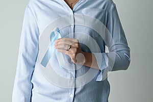 November light blue ribbon on woman hand with copy space, Prostate cancer awareness month, men`s health concept
