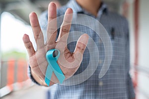 November Prostate Cancer Awareness month, Man in blue shirt with hand holding Blue Ribbon for supporting people living and illness