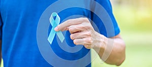 November Prostate Cancer Awareness month, Man in blue T shirt with hand holding Blue Ribbon for supporting people living and