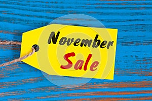 November Sale, price tag on blue wooden background