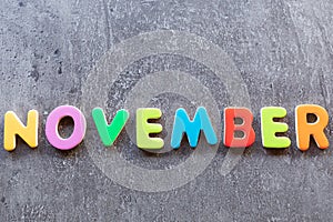November word written with colorful letters on grey granite stone background
