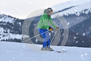 A novice adult skier carefully descends the snowy slopes during a snowfall