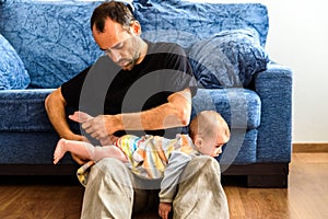 Novice father changing clothes to his baby with effort in the living room of his house