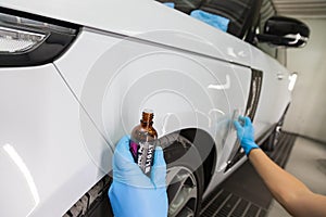 The process of applying a nano-ceramic coating Ceramic Pro 9h and Light on the car`s fender by a worker with a sponge and chemica