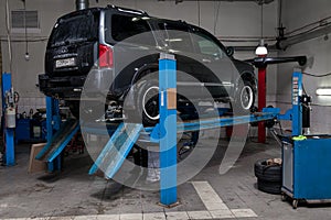 Used gray car Infiniti QX56 stands on the stand wheel alignment convergence of the car in the workshop for repair of vehicles Auto