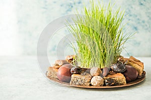 Novruz traditional tray with green wheat grass semeni or sabzi, sweets and dry fruits pakhlava on white background. Spring equinox