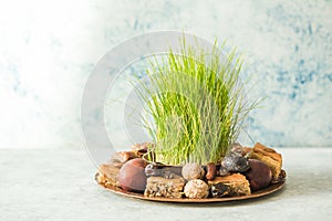 Novruz traditional tray with green wheat grass semeni or sabzi, sweets and dry fruits pakhlava on white background. Spring equinox
