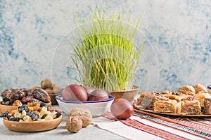 Novruz traditional tray with green wheat grass semeni or sabzi, sweets and dry fruits pakhlava on white background. Spring equinox