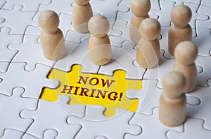 Now hiring text on missing jigsaw puzzle with wooden dolls.. Hiring and employment concept