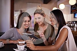 Now that looks good. three friends making plans in a coffee shop with a digital tablet.