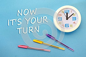 NOW IT`S YOUR TURN - lettering on a blue background and clock