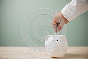 For now, savings money, financial, accounting, and business for future. Man`s hands holding putting coins into a white piggy bank