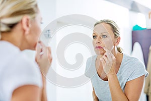 Now is the time to look after your skin. a mature woman inspecting her skin in front of the bathroom mirror.