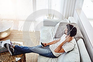 Now this is what stressless sounds like. a man relaxing on the sofa while using his phone and headphones.