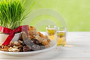 Nowruz holiday concept - grass, baklava sweets, nuts and seeds