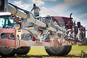 Nozzles on the spray bar, against the background of the sprayer and the person standing on the barrel, during refueling
