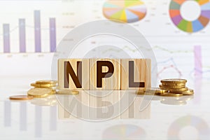 NPL the word on wooden cubes, cubes stand on a reflective surface, in the background is a business diagram