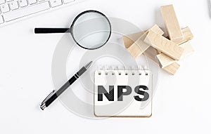 NPS word written on notebook with block magnifier and pen , business concept