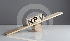 NPV on wooden cubes on a wooden balance , business concept