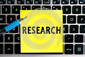 nscription `Research` on a yellow sheet of sticker paper on the background of a computer keyboard