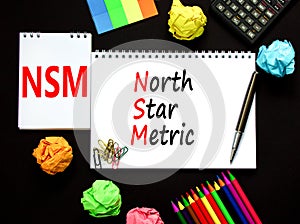 NSM north star metric symbol. Concept words NSM north star metric on white note on a beautiful black background. Calculator and